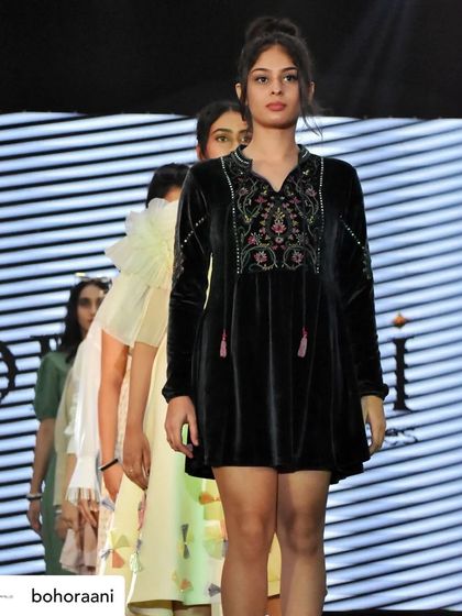 A full lineup of models on the runway showcasing our collection. This image features our black velvet tunic dress at the forefront, followed by other contemporary pieces.