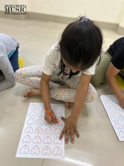 A young student focuses intently on a rhythm notation exercise. We introduce foundational music theory concepts early on, using creative, age-appropriate worksheets to make it feel like play.