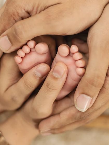 Both parents' hands cradling their baby's feet. A beautiful symbol of family and protection.