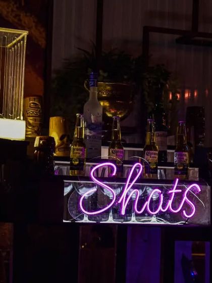 A dedicated 'Shots' station with a neon sign. This is where the fun is, with a full setup for Jello shots, Jager bombs, and other party starters.