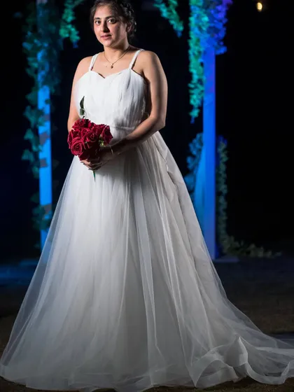 Here is the classic white tulle gown I designed for a client's pre-wedding shoot. It features a simple sweetheart neckline and a full, layered skirt that creates a timeless bridal look. I styled it with a simple bouquet of red roses for a pop of classic color.