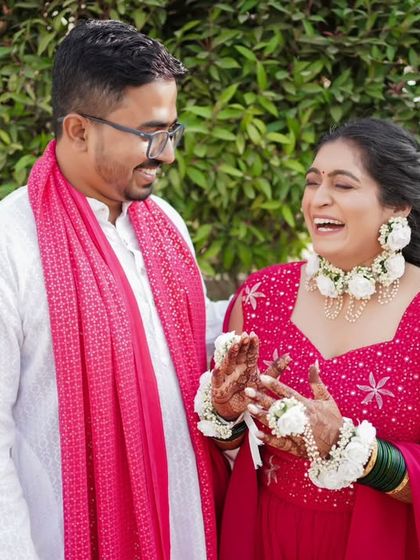 A candid moment of laughter between the couple during their Haldi ceremony, dressed in vibrant pink.