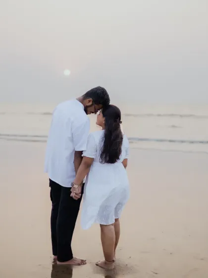 A quiet, tender moment between the couple on the beach, holding hands and looking at each other.
