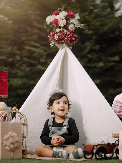 A sweet, candid moment during a first birthday celebration. The teepee and teddy bears create a cozy and playful backdrop for this little one's special day.