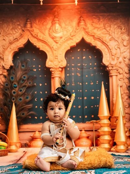 A wider view of the magnificent Little Krishna setup, showcasing the golden pillars and peacock-feather-adorned backdrop.