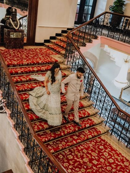 A grand shot of the couple descending a magnificent staircase, their outfits and the setting creating a picture of pure elegance.