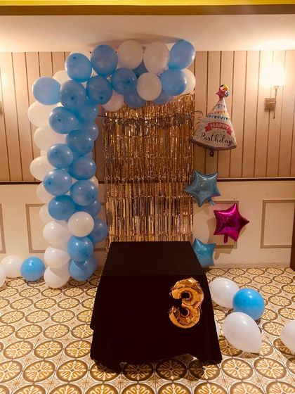 A sweet and simple birthday decoration for a little one turning three. I used blue and white balloons for the arch, a gold fringe curtain, and a large number '3' foil balloon by the cake table.