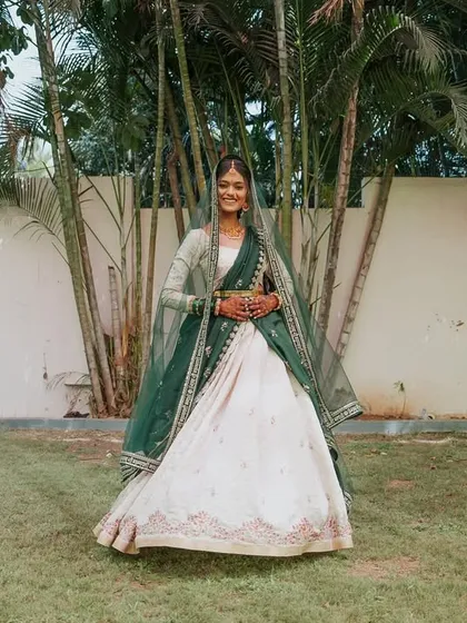 A full-length portrait of the bride in her elegant Haldi outfit, smiling in a beautiful garden setting.