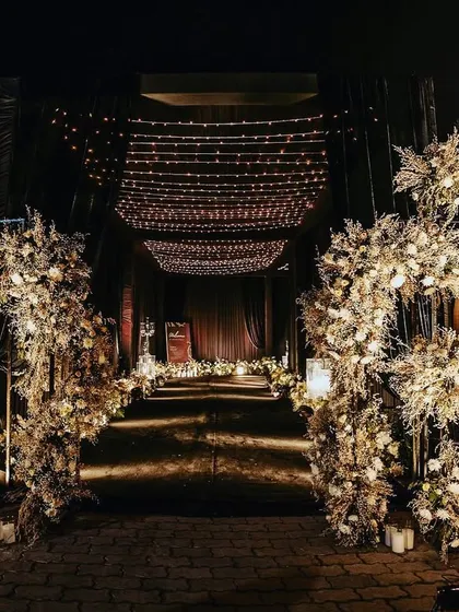 A breathtaking floral archway made of dried elements and white blooms, illuminated by warm lights. This entrance set a magical, rustic-luxe tone for the evening's celebrations.