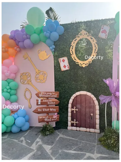 A close-up of the Wonderland entrance details, including a grass wall, playing cards, and a "This way to Wonderland" sign.