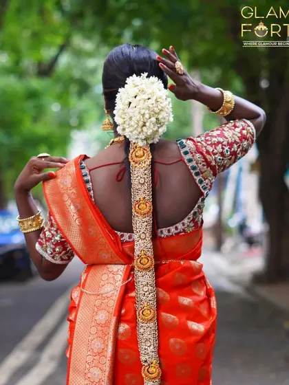 The back view of a traditional South Indian bridal hairstyle. Our hair styling classes cover creating these elaborate braids, known as 'Jada', complete with floral and gold accessories.