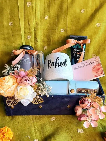 This personalized Rakhi hamper for a brother includes a custom mug and wallet, premium coffee, and grooming essentials, all beautifully arranged with floral touches in a suede box.