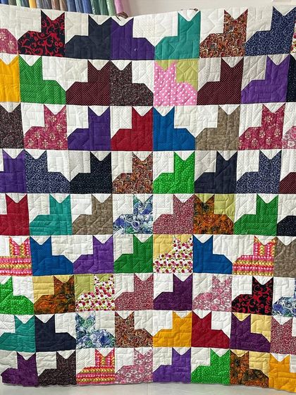 A playful and colorful "Cat City" quilt, where each block is a stylized cat silhouette made from a different fun fabric.