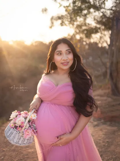 A sun-kissed outdoor portrait. The golden light of sunset adds a magical glow to this shot, highlighting her happy expression as she holds a basket of flowers.