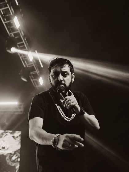 A singer on stage, captured in a moody black and white shot. The strong spotlight creates a dramatic contrast, focusing all attention on the performer.