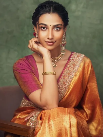A close-up portrait from our traditional silk saree shoot. The warm, golden tones of the saree are complemented by the intricate gold jewelry and the model's elegant pose.