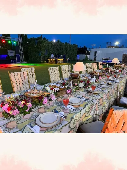 An elegantly set long dining table for an outdoor event, decorated with flowers and candles, showcasing our tablescape services.