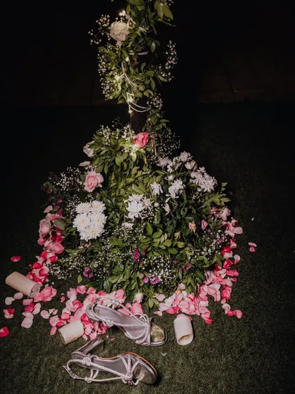 The aftermath of a celebration. The bride's sandals left on the grass among flower petals, a quiet detail that tells a story of a night of dancing.
