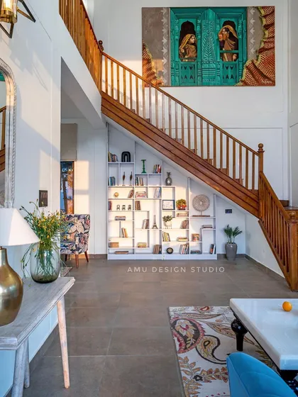 We designed a custom bookshelf under the staircase to maximize space, complemented by a large, traditional painting that adds character to the entryway.