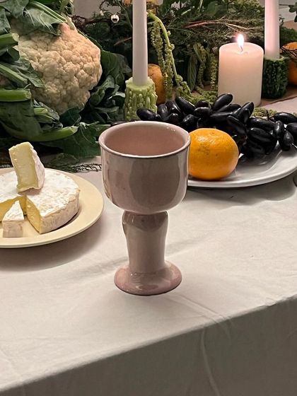 The 'Kāge' goblet, with its soft pink hue, is a perfect complement to the warm candlelight. These pieces are designed to bring joy to your life.