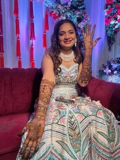A proud bride showing her palm, covered in our intricate and detailed mehandi.