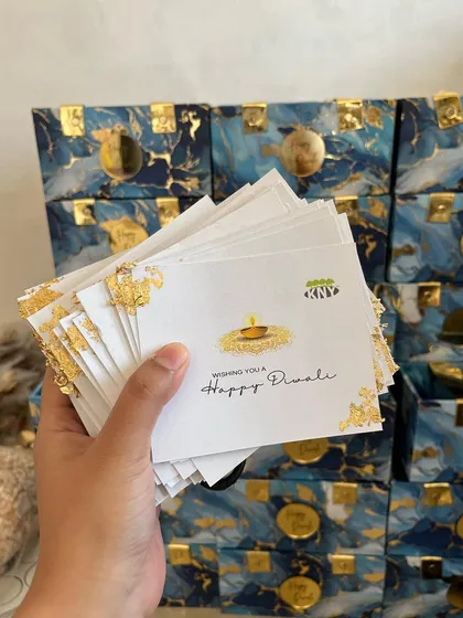A stack of custom-designed "Happy Diwali" cards with gold foil accents, ready to be included in our gift hampers.