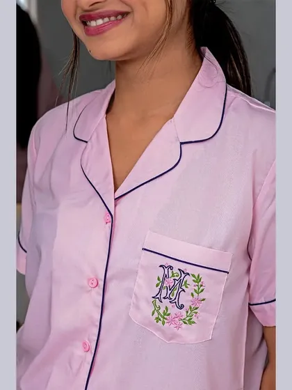 Highlighting personalization is key for many brands. This shot clearly displays the custom monogram embroidery on the pocket of a pink pajama shirt, a detail that is a major selling point.