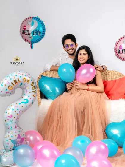 A fun and festive gender reveal themed maternity shoot. Surrounded by pink and blue balloons, this couple celebrates their pregnancy with bright smiles and a playful atmosphere in our studio.