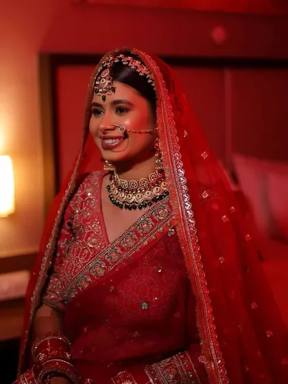 The joy of a bride in her final look. This candid shot captures her happiness and the beautiful, radiant makeup under soft lighting.
