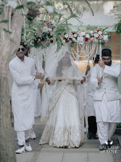 A bride makes her grand entrance under a beautiful floral canopy. This traditional element adds a touch of royalty and grace to the wedding procession.