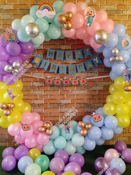 A circular Cocomelon balloon backdrop in pastel colors, perfect for a first birthday party.
