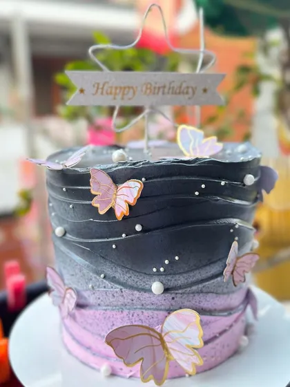 A stunning ombre cake in black and pink, decorated with delicate butterflies.