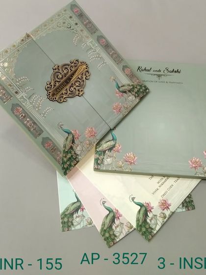 A gate-fold invitation in a lovely sage green, decorated with peacocks and lotus flowers. The ornate wooden clasp and three inserts make this a complete and beautiful package.