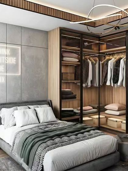 This bedroom design is perfect for the fashion-conscious, featuring a glass-fronted open wardrobe system. The industrial-style lighting and 'Think Outside The Box' neon sign add a cool, urban vibe.