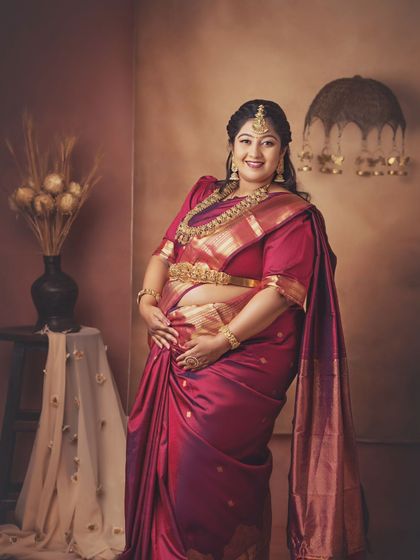 A beautiful standing portrait of the mom-to-be, her hand resting gently on her bump. The traditional styling and warm lighting create a stunning and regal image.