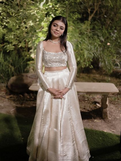 A full-length view of the sister of the bride's chic sangeet outfit. The shimmering fabric and clean silhouette make it a timeless choice for any wedding celebration.