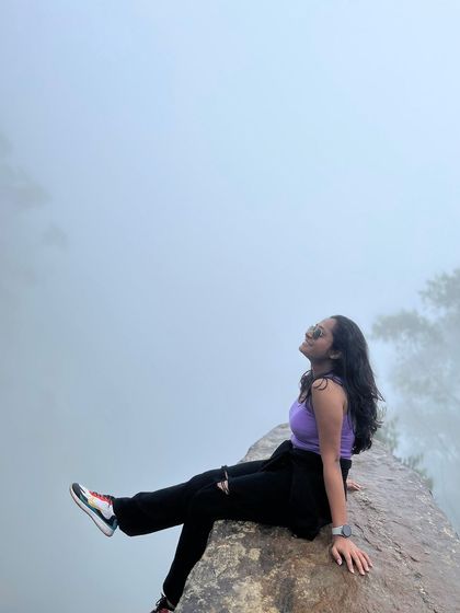 A trekker relaxing on a rock at a misty viewpoint.