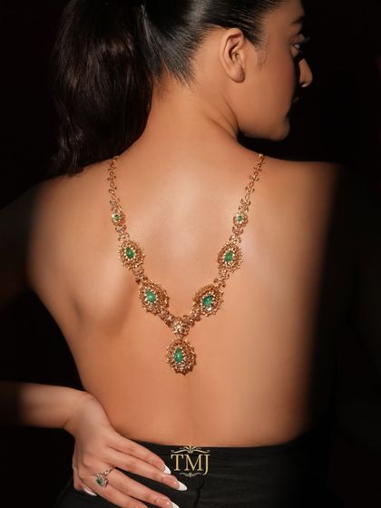 A cascade of emerald dreams. This unique emerald and gold necklace is designed to be worn down the back, creating a surprising and dramatic statement.