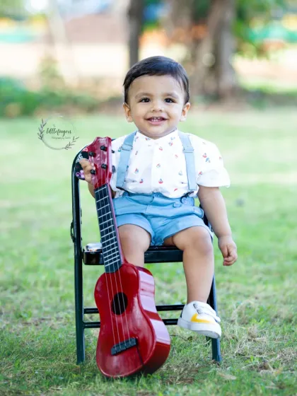 A happy one-year-old boy with the biggest smile and his little red guitar.