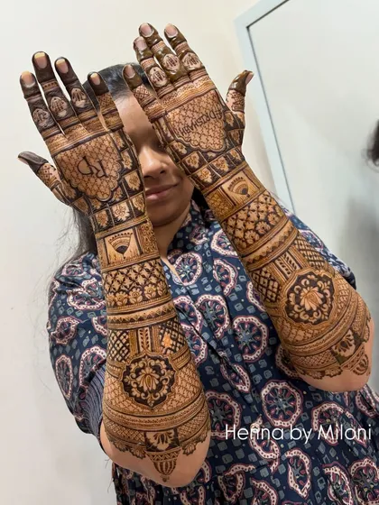 A full-coverage bridal mehendi that extends up the arm. This design is filled with a variety of traditional patterns, including checks, florals, and paisleys, for a truly grand look.