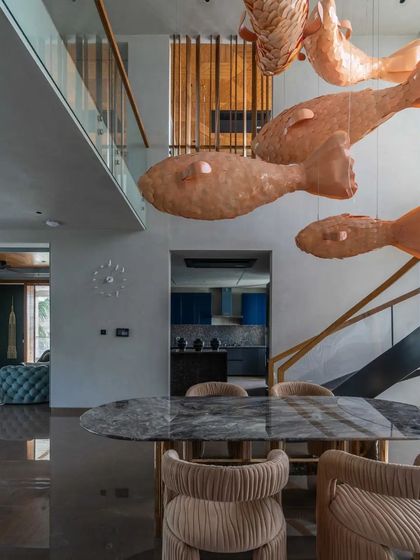 A view from the dining table towards the living area, showing how the whimsical fish chandelier connects the different zones of the open-plan home.
