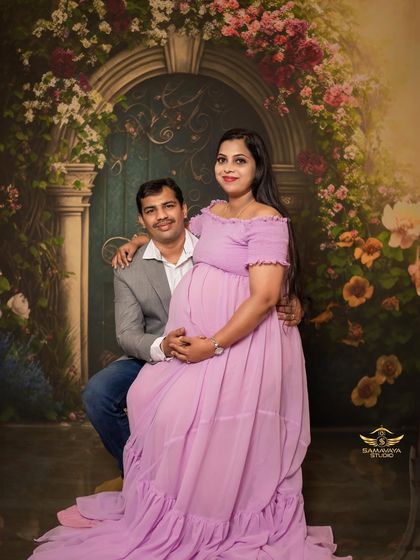 A sweet, seated portrait of the couple, framed by a beautiful floral backdrop. This is a classic and timeless maternity shot.