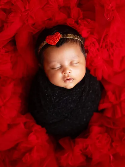 An overhead shot showing the baby nestled in a sea of red tulle. This perspective creates a dramatic and artistic portrait.