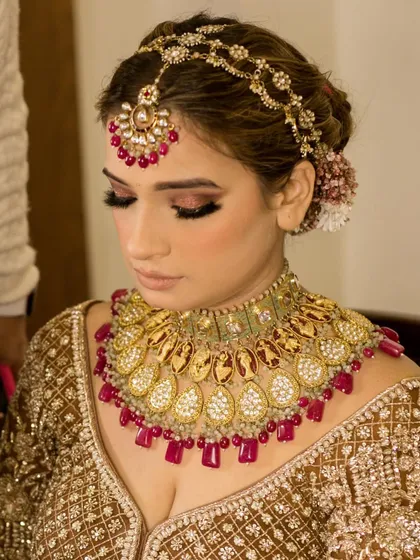A detailed shot of the polki and ruby necklace and the matching matha patti, showcasing the vibrant colors and intricate design.