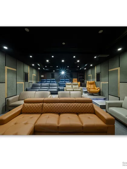 Another view of the home theater showroom, with the projector light creating a focal point. The acoustically treated walls and professional lighting demonstrate the technical quality of the installations.