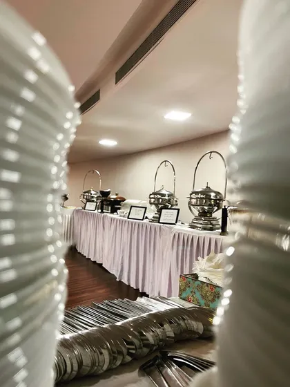 A glimpse of my buffet setup, viewed between stacks of clean plates, ready for service. I focus on making the entire dining experience organized and elegant.