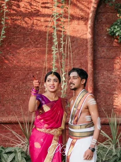 A beautiful moment from a traditional Kalyanam. The couple is framed against a backdrop of red laterite stone, a classic element of South Indian architecture that we love to incorporate.