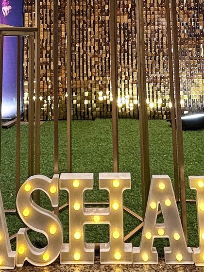 Light-up marquee letters spelling "ASHAN" against a gold shimmer wall. This is a fantastic way to personalize a photo booth area for any event.