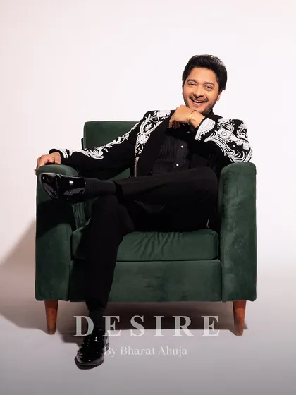 Seated in confidence, this shot showcases the full silhouette of the black embroidered blazer and matching trousers. It's a look of pure elegance and modern sophistication.