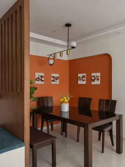 We created a distinct dining nook using a bold terracotta accent wall and an arched doorway. The dark wood dining set provides a rich contrast, and the modern pendant light serves as a stylish focal point for family meals.
